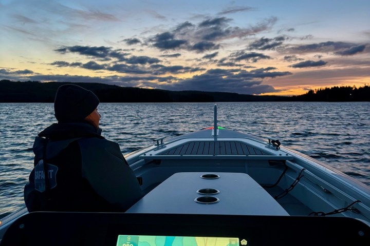 Person in a boat at sunset, using a GPS navigation system.