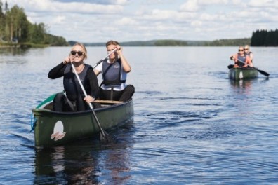 People canoeing on a calm lake under a sunny sky.