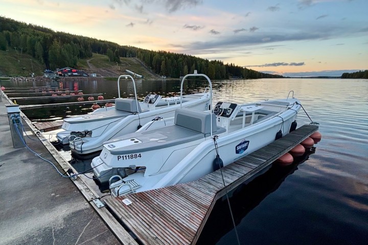 Docked boats on a calm lake at sunset with a forest backdrop.