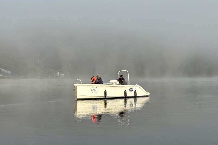Two people on a pedal boat in a misty lake.