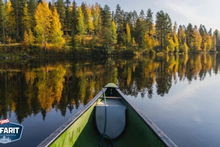 Canoe on lake with autumn trees reflecting in the water.