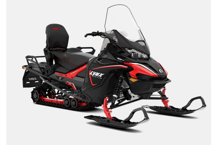 Red and black snowmobile with windshield on a white background.