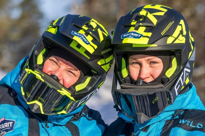 Two people in blue jackets and helmets with yellow patterns, standing outdoors.