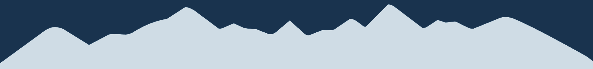 Silhouette of jagged mountain peaks against dark blue sky.