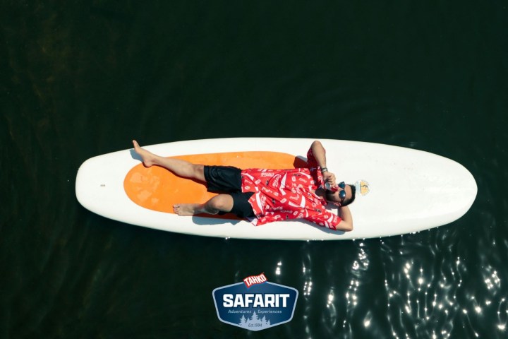 Person in red shirt relaxing on a paddleboard in water.