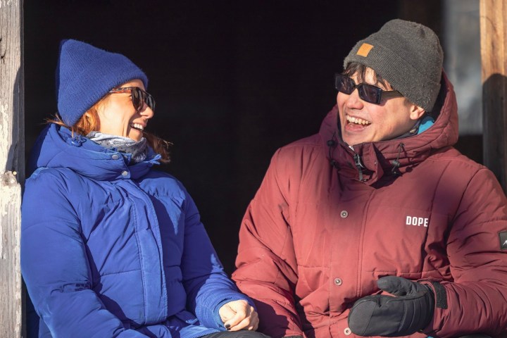 Two people in winter clothes laughing in the sun.