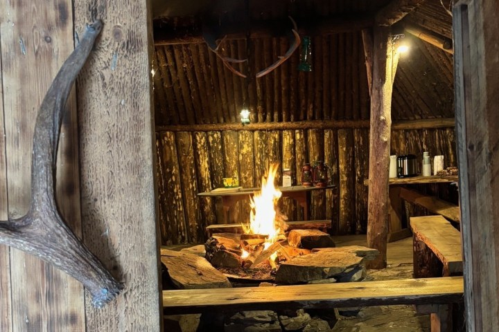 Rustic wooden cabin interior with central fire pit.