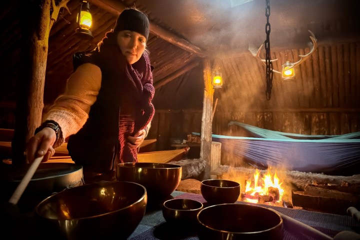 Person playing bowls in a rustic room with hanging lights and a fire.
