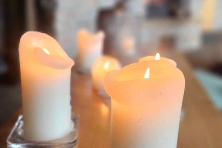 Lit candles on a wooden table near a fireplace.
