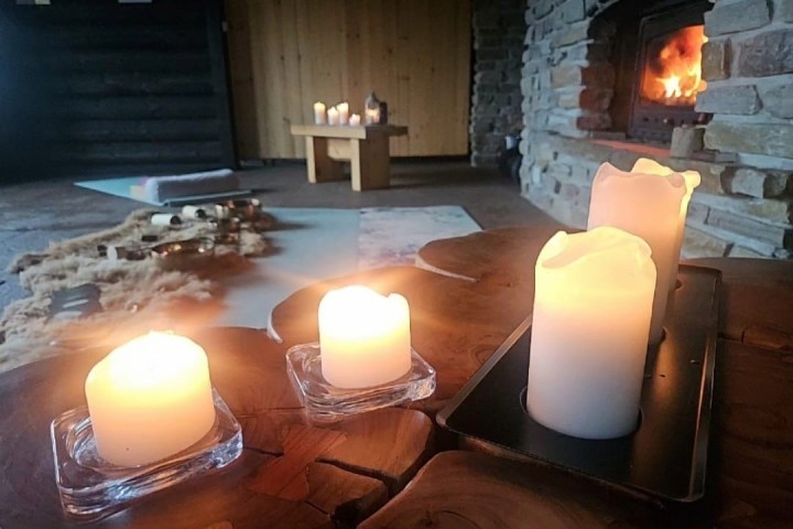 Cozy room with lit candles on a table, fireplace in the background.