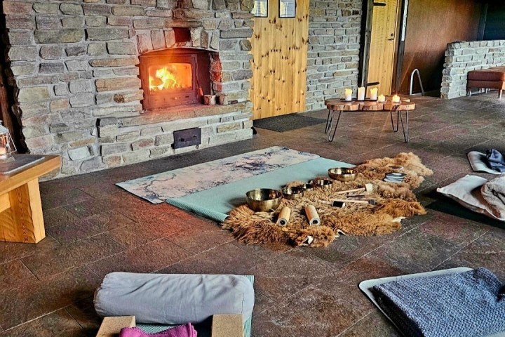 Cozy room with yoga mats, cushions, candles, and a lit fireplace.